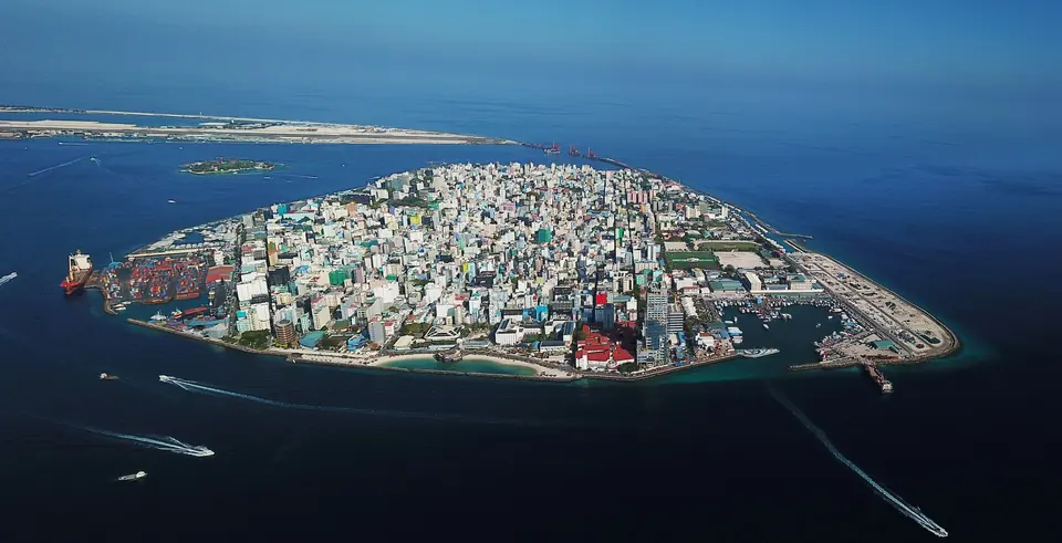 Aerial view of Malé surrounded by reef, with harbour berths and vessel traffic in the channel.