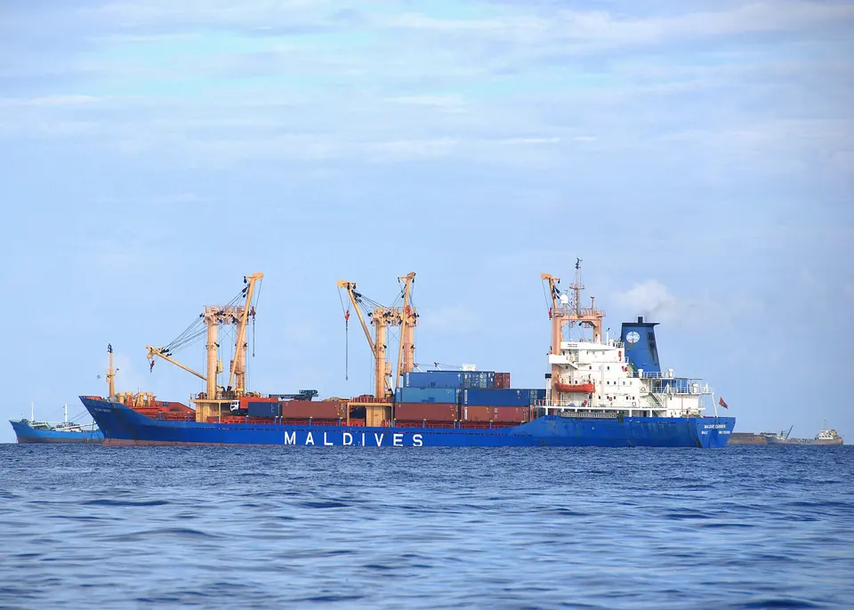 Cargo vessel with deck cranes working at anchor in Malé port.