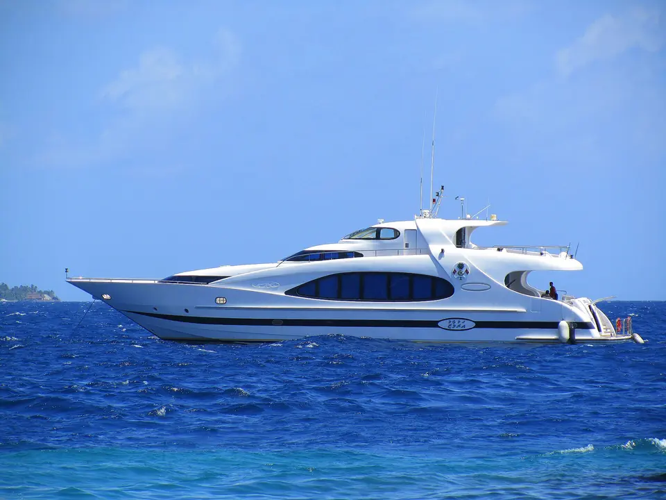Motor yacht under way over shallow reef water in the Maldives.